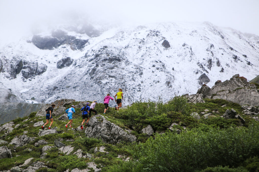 a group of mountain runners heading toward a snowy mountain