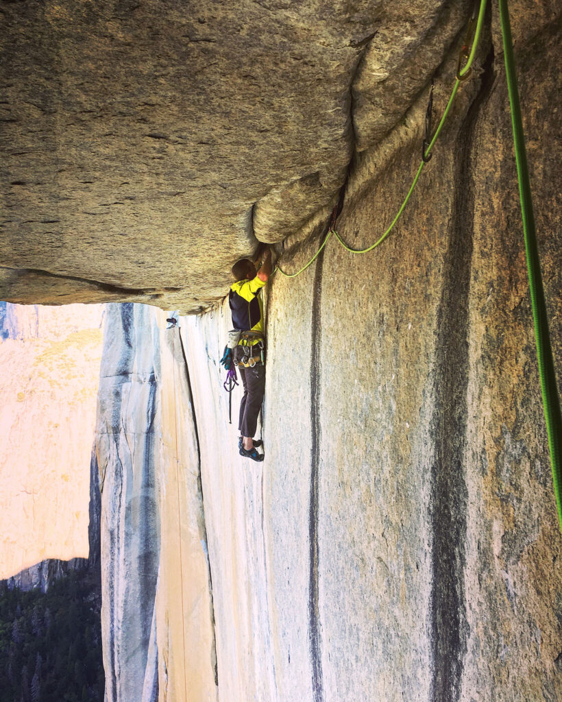 A climber on a crux with a perpendicular wall above him.