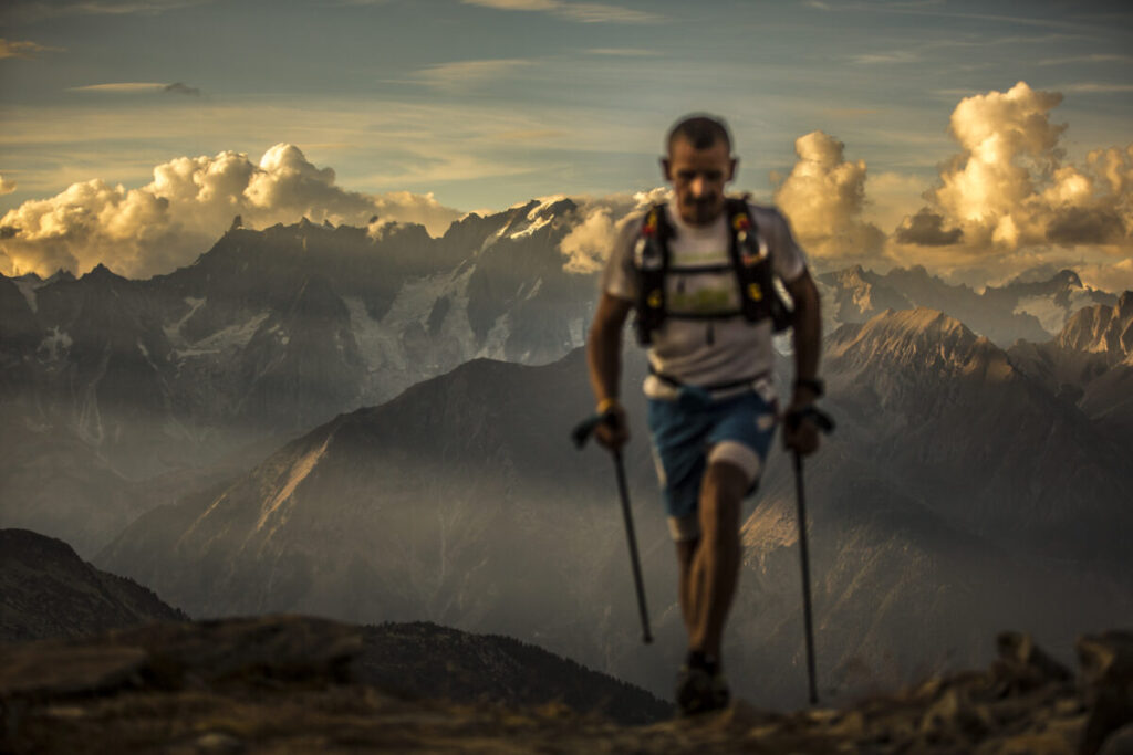 A blurry image of a person walking on a mountain using trekking poles.