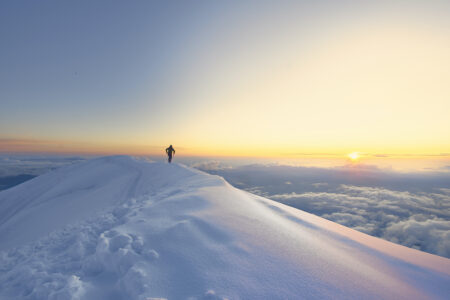 A person on a mountain ridge at sunset.