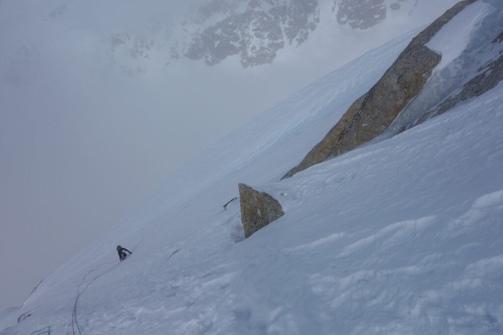 A climber going up a steep snow slope.