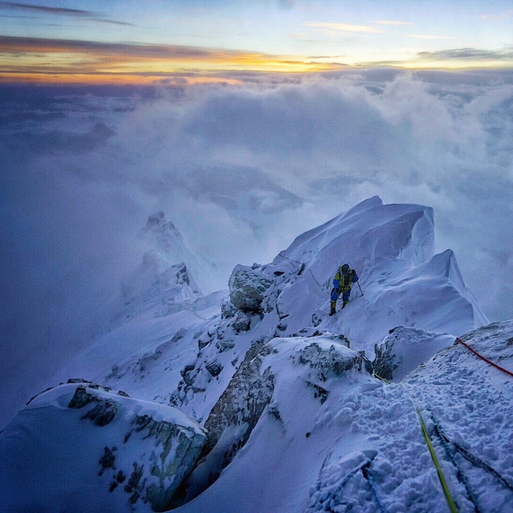 A climber on a mountain ridge at high altitude.