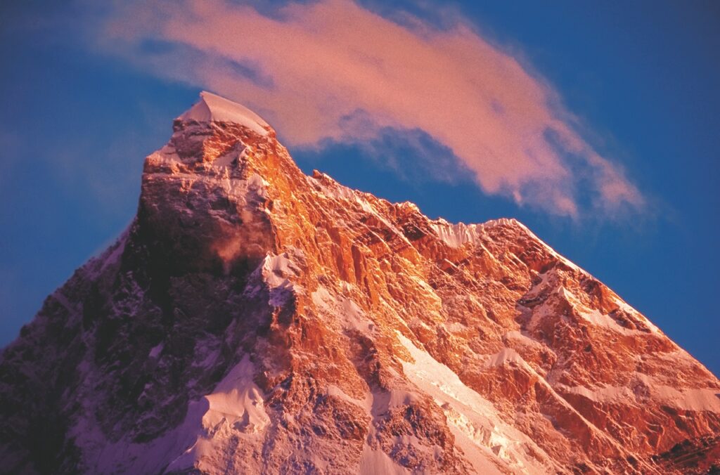 A mountain summit turning crimson red at sunrise.