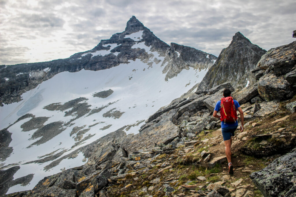 A man running in the mountains with snow on the ground.