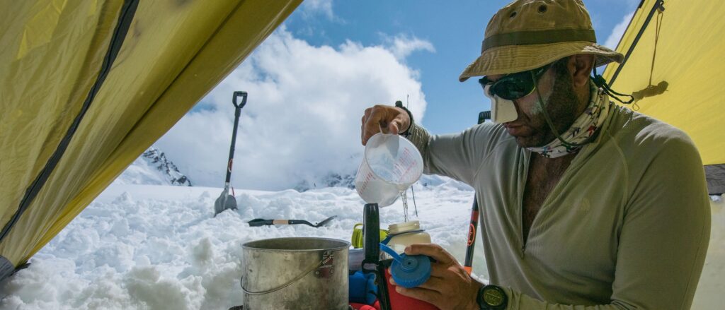 A mountaineer boiling snow for water.